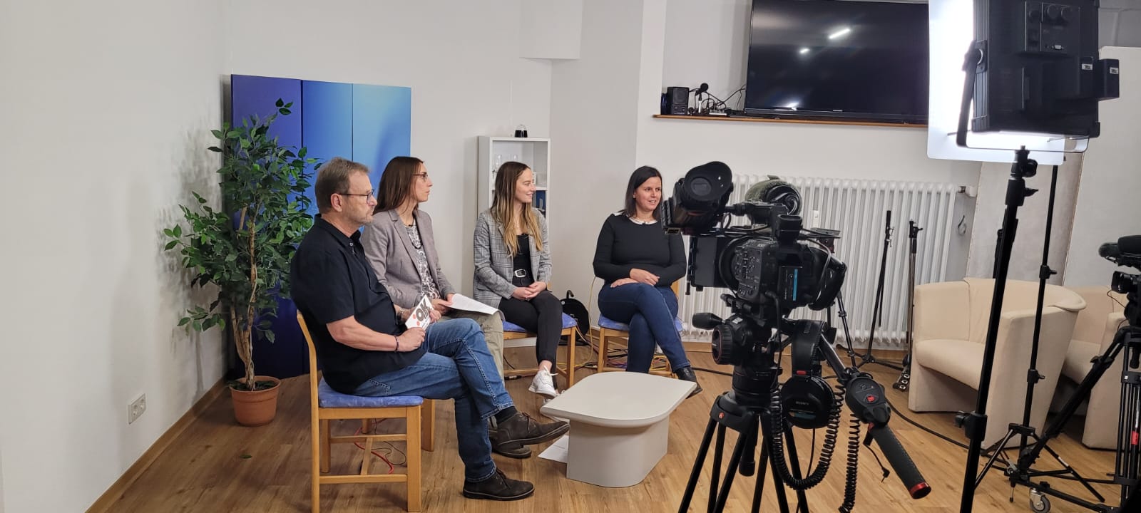 Personen sitzen in einem Aufnahmestudio und unterhalte sich.